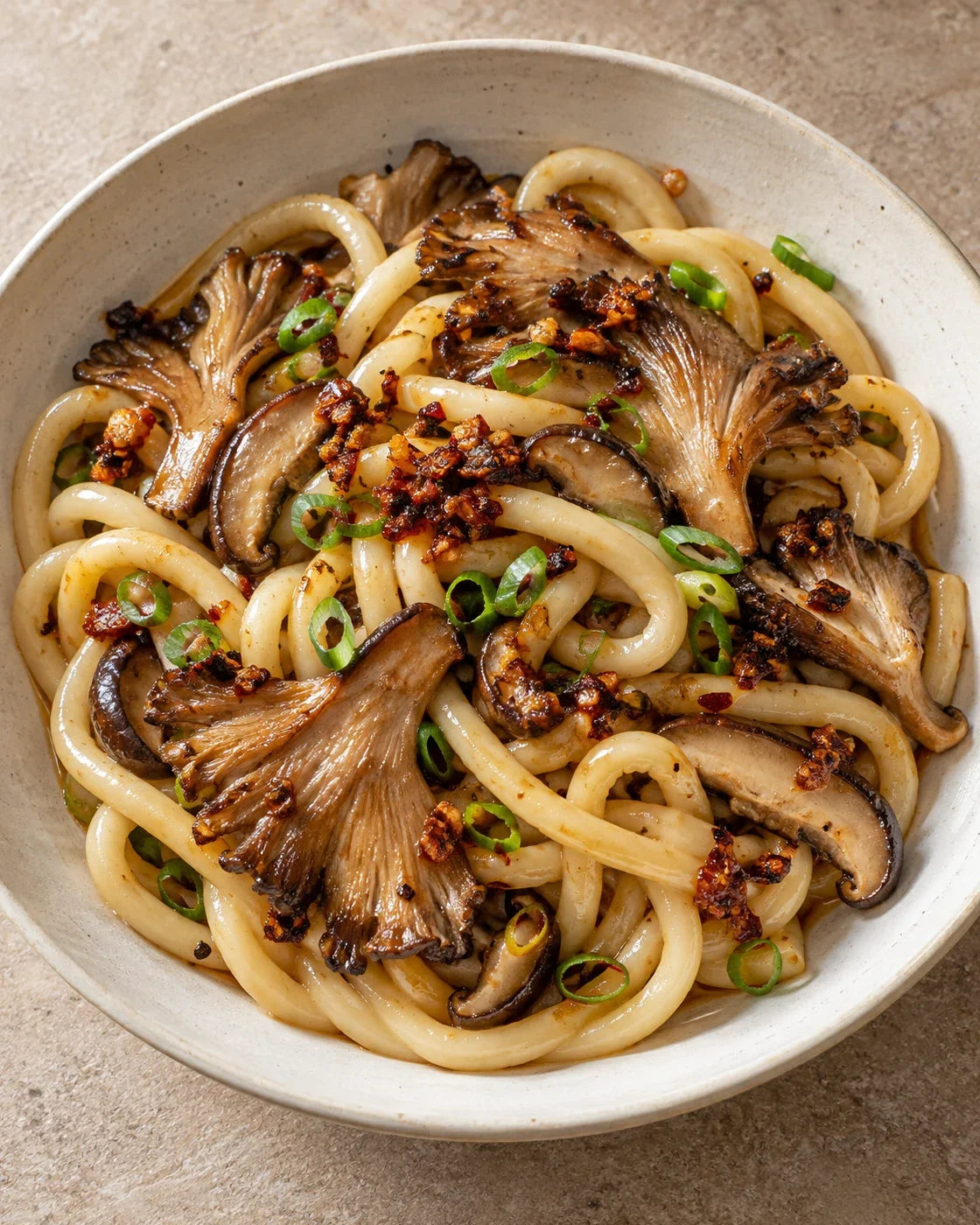 Thick udon with browned oyster and shiitake mushrooms, scallions, and visible garlic-shallot chili crisp