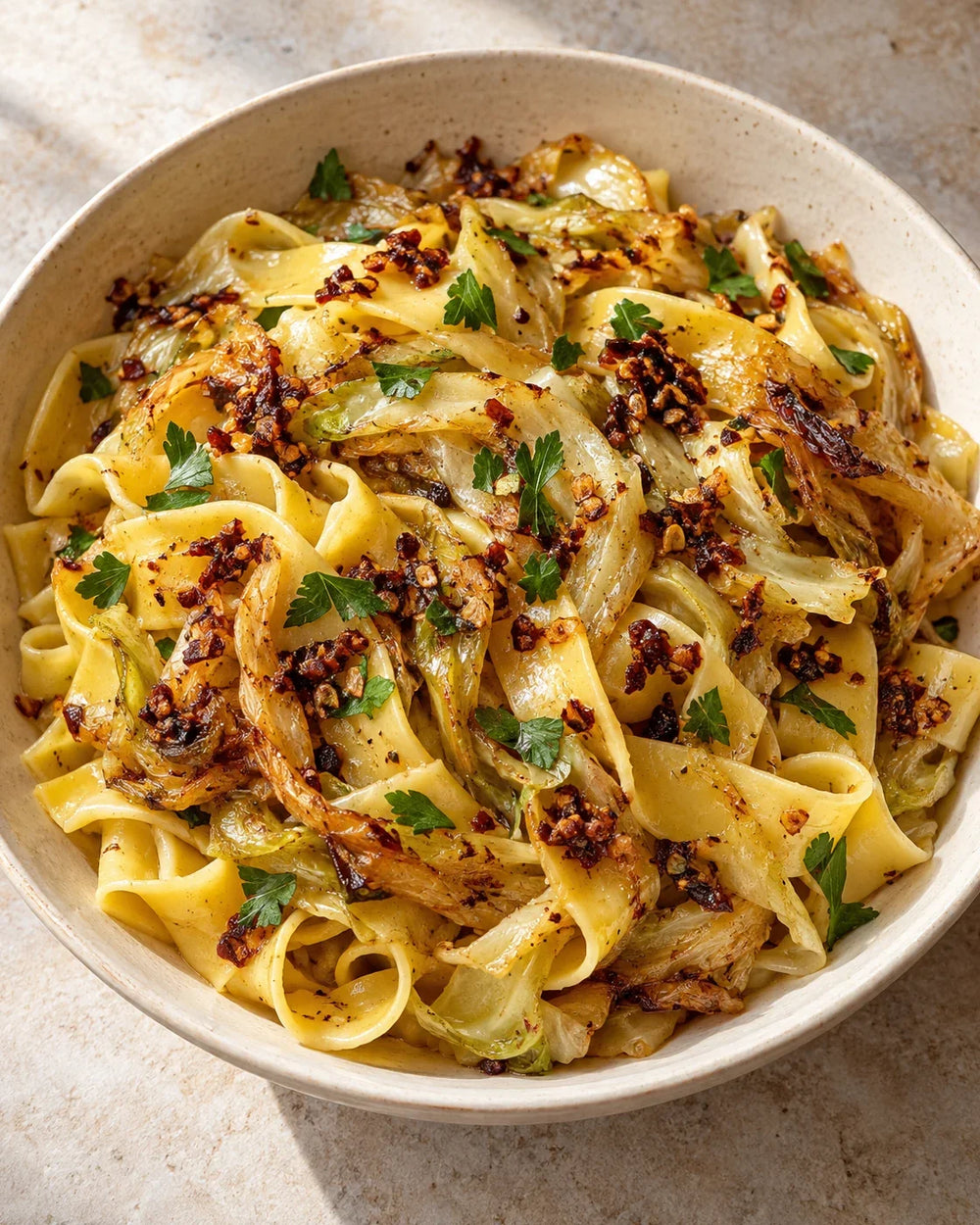 Wide egg noodles with golden cabbage ribbons, parsley, and red-brown garlic-shallot chili crisp